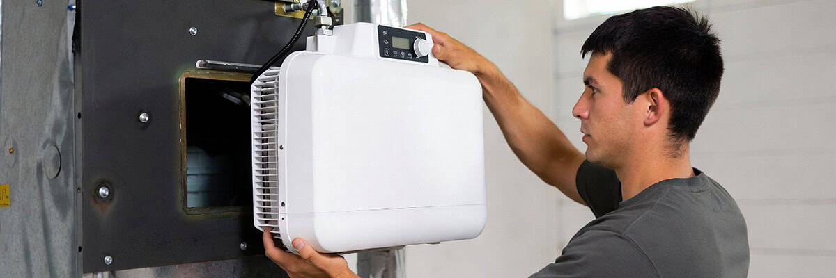 HVAC technician installing whole-home humidifier in Colorado Springs home
